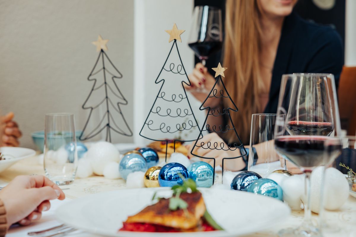 Weihnachtlich dekorierter Tisch mit Hauptgang und Rotwein