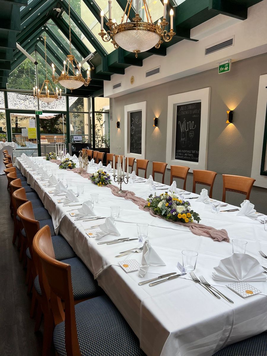Festlich gedeckte Tafel mit Blumen und Kerzenleuchtern im Wintergarten